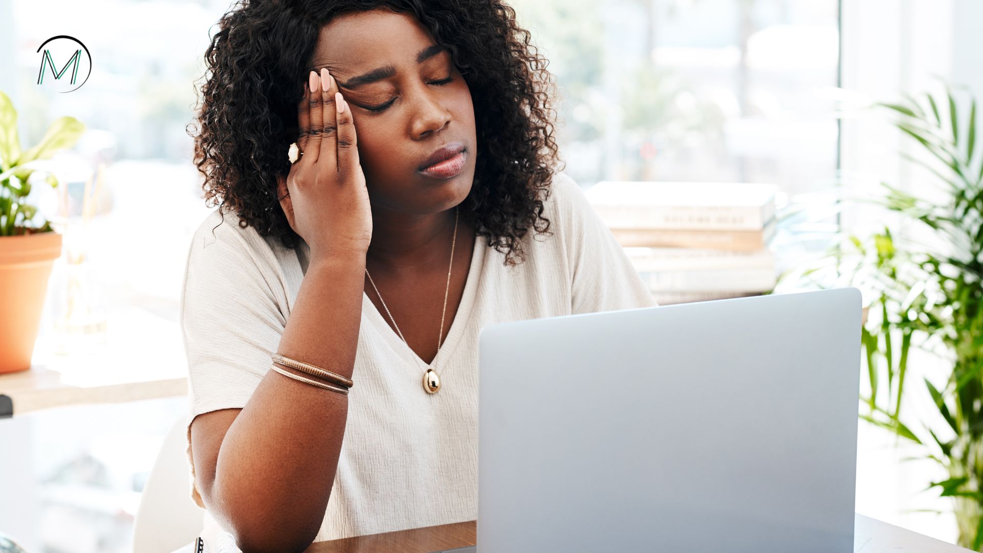 Colaborador sentado à mesa de trabalho com expressão de cansaço, representando sintomas de burnout no ambiente corporativo.